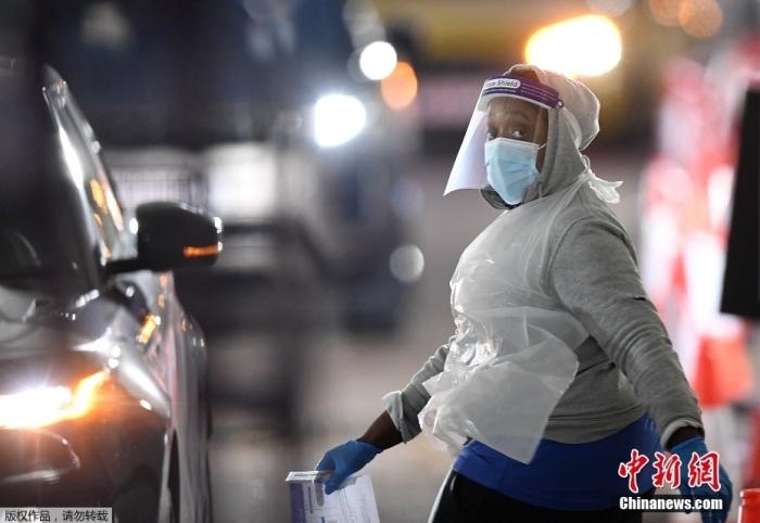 當(dāng)?shù)貢r(shí)間12月18日，英國(guó)政府公布的數(shù)據(jù)顯示，當(dāng)天英國(guó)新增奧密克戎毒株感染病例10059例。鑒于奧密克戎毒株感染病例激增，住院人數(shù)不斷上升，倫敦市長(zhǎng)宣布倫敦進(jìn)入“重大事故”狀態(tài)。圖為倫敦的一個(gè)免下車檢測(cè)中心，一名醫(yī)務(wù)工作者正準(zhǔn)備對(duì)司機(jī)進(jìn)行核酸檢測(cè)。