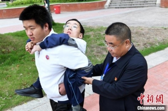 朱金祥背著鐘華強(qiáng)去教室上課的路上，也經(jīng)常碰到值班的校領(lǐng)導(dǎo)和老師前來搭把手。 卓忠偉 攝