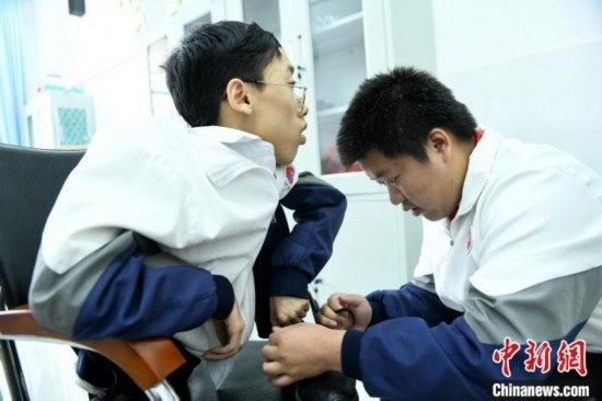 江西省南康中學(xué)北校區(qū)的高三學(xué)生朱金祥(右)正在給鐘華強(qiáng)(左)系好鞋帶。 卓忠偉 攝