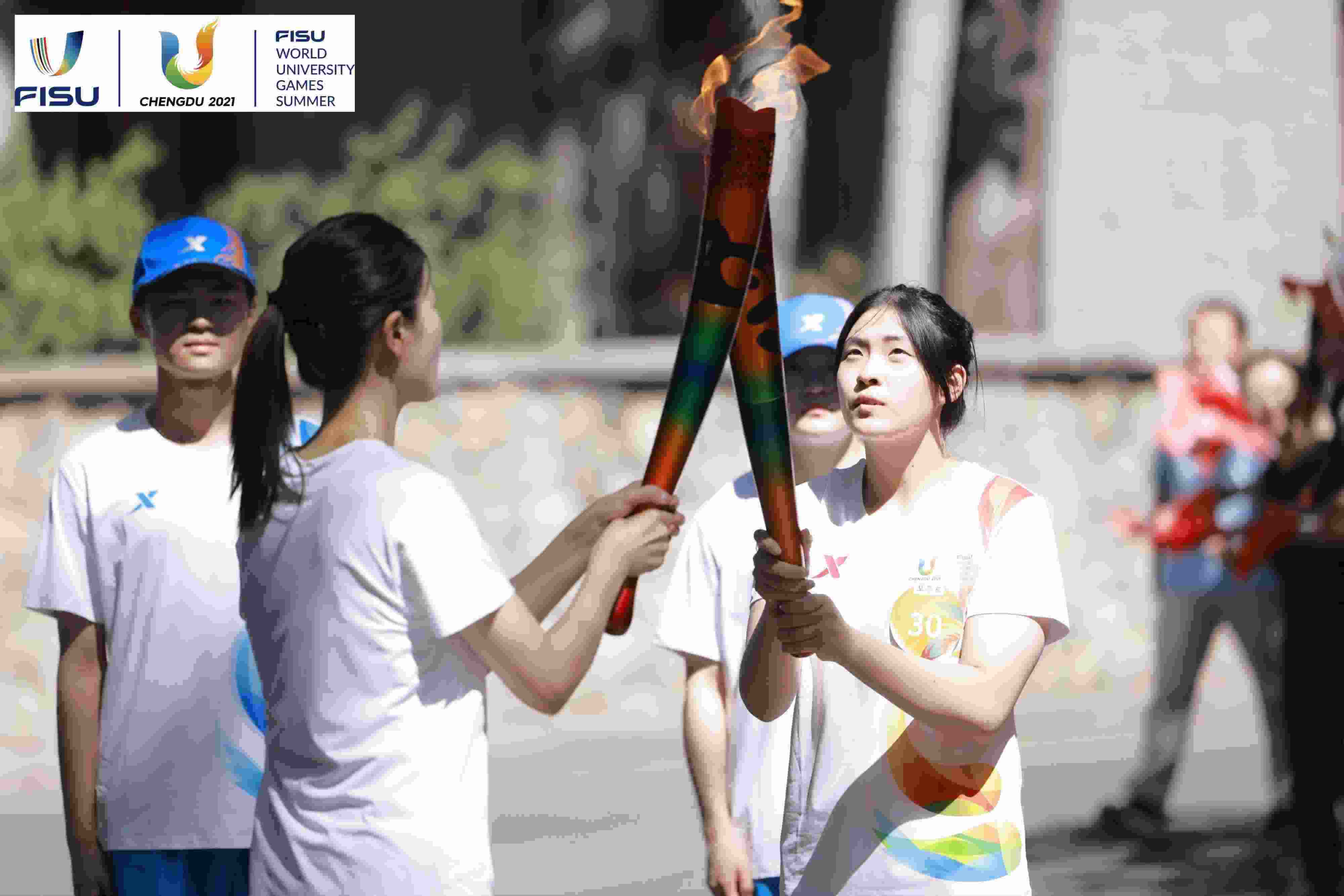 兩名大運會火炬手進行火炬?zhèn)鬟f。 圖片來源：成都大運會執(zhí)委會供圖