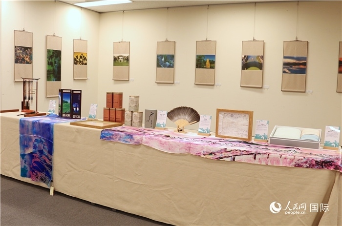 現(xiàn)場展出的馮學(xué)敏攝影作品與湖州市特色工藝品。（人民網(wǎng) 許可攝）