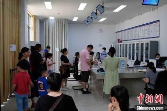 圖為在戶籍辦證廳內(nèi)排隊等待的家長和孩子。劉俊聰 攝