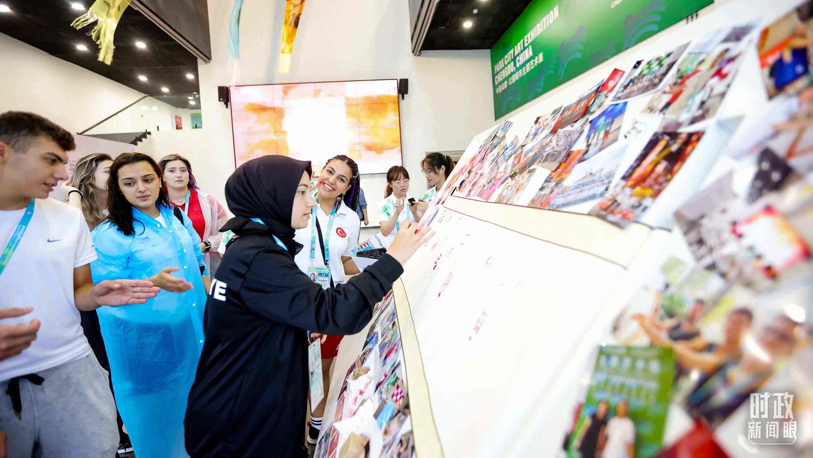 各國青年運(yùn)動員正在參觀成都大運(yùn)村內(nèi)的“雪山下的公園城市，煙火里的幸福成都”主題藝術(shù)展。（總臺央視記者魏幫軍拍攝）