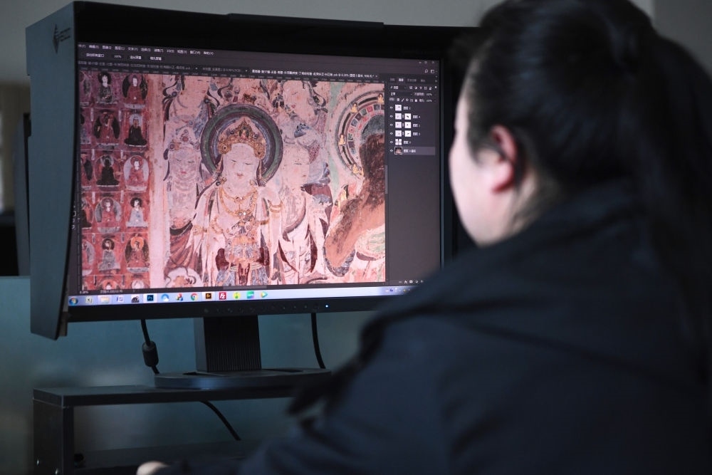 敦煌研究院文物數(shù)字化保護團隊圖像處理人員年海麗在拼接壁畫圖像（2023年4月25日攝）。數(shù)字化探索為莫高窟的保護與傳承開辟了全新路徑，數(shù)字技術讓敦煌文物走出洞窟，跨出國門，走向“永久保存、永續(xù)利用”。新華社記者 陳斌 攝