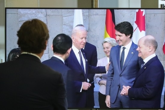 2022年3月24日，在比利時(shí)布魯塞爾的北約總部，一名男子觀看屏幕上美國總統(tǒng)拜登（右四）、歐盟委員會(huì)主席馮德萊恩（右三）、加拿大總理特魯多（右二）、德國總理朔爾茨（右一）出席七國集團(tuán)峰會(huì)合影儀式的畫面。新華社記者鄭煥松攝