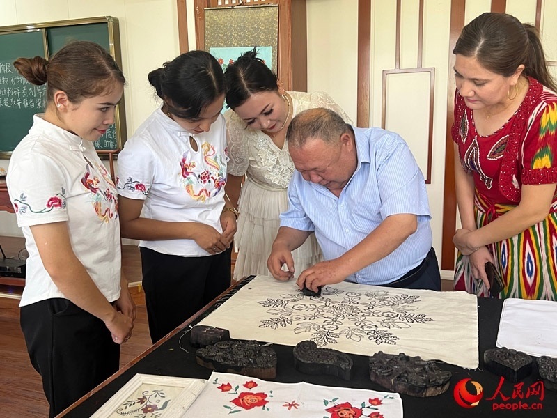 國家級非物質文化遺產模戳印花布技藝傳承人吾吉阿西木?吾舒爾展示模戳印花布的制作過程。人民網記者 常雪梅攝