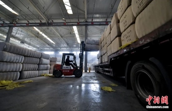 新疆喀什綜合保稅區(qū)，喀什啟路國際貿(mào)易有限公司的倉庫內(nèi)，工人正在裝載從塔吉克斯坦和烏茲別克斯坦進口的棉花。劉新攝