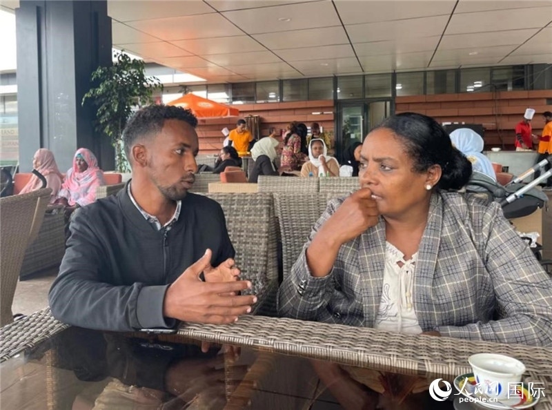 約漢斯（圖左）與德貝拉在友誼廣場咖啡廳交談。人民網(wǎng)記者 趙艷紅攝