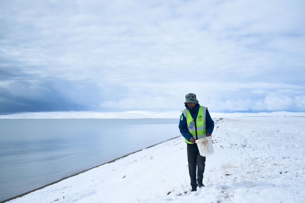 2021年10月20日，在青海省果洛藏族自治州瑪多縣扎陵湖鄉(xiāng)勒那村，三江源國(guó)家公園黃河源園區(qū)生態(tài)管護(hù)員在扎陵湖邊撿拾垃圾。新華社記者 張龍 攝