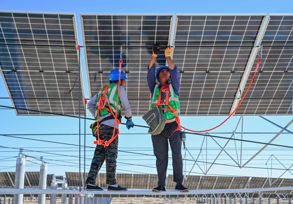 2023年7月22日，工人在位于內(nèi)蒙古杭錦旗庫(kù)布其沙漠億利生態(tài)示范區(qū)的蒙西基地庫(kù)布其200萬(wàn)千瓦光伏治沙項(xiàng)目工地安裝光伏板。新華社記者 劉磊 攝
