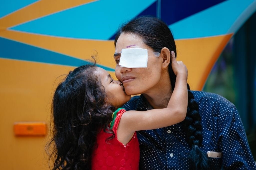 2019年3月15日，在柬埔寨磅湛省醫(yī)院，即將接受白內(nèi)障手術(shù)的患者孫美樂接受女兒的親吻祝福。在接受了中國醫(yī)療隊的白內(nèi)障義診手術(shù)后，她的視力逐步恢復(fù)，生活有了新的光明和希望。