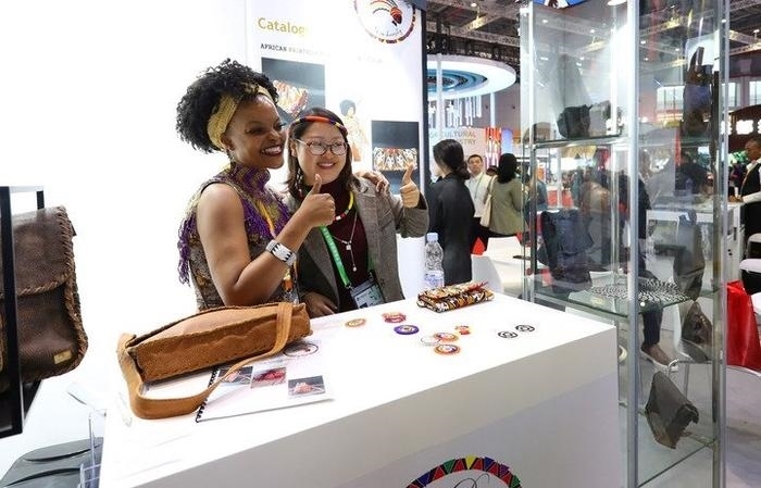 11月6日，一位參觀者（右）在第六屆進博會國家展南非展臺試戴傳統(tǒng)首飾。