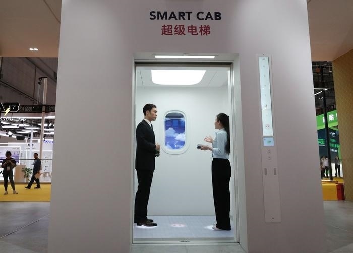 11月5日，工作人員（右）在第六屆進博會上向參觀者介紹奧的斯公司全新推出的超級電梯。