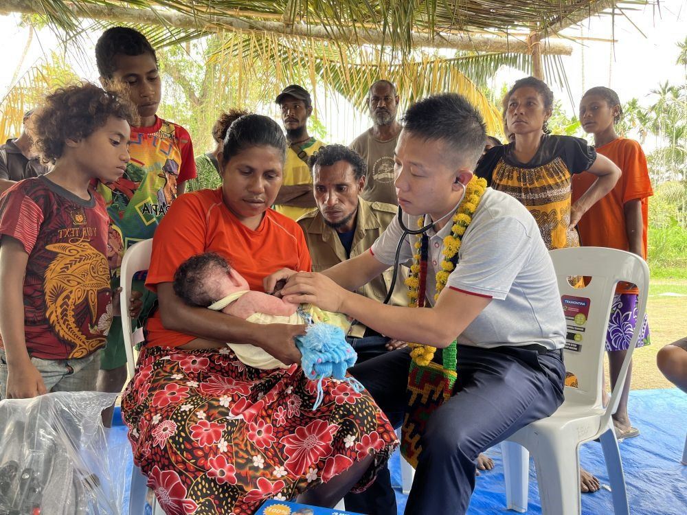 2023年8月5日，在巴布亞新幾內(nèi)亞中央省的一個村莊里，第12批援巴新中國醫(yī)療隊副隊長、新生兒科副主任醫(yī)師劉振球為嬰兒泰樂聽診檢查。泰樂出生時患有重癥，一度生命垂危，經(jīng)過劉振球與當?shù)蒯t(yī)護人員的救治最終痊愈。從2002年起，中國連續(xù)向巴新派出12批醫(yī)療隊，為提高巴新醫(yī)療衛(wèi)生水平作出積極貢獻。