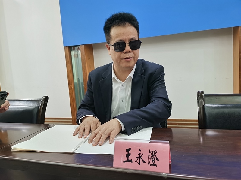 全國人大代表王永澄正在閱讀盲文版代表建議答復(fù)。本報(bào)記者 張 璁?dāng)z