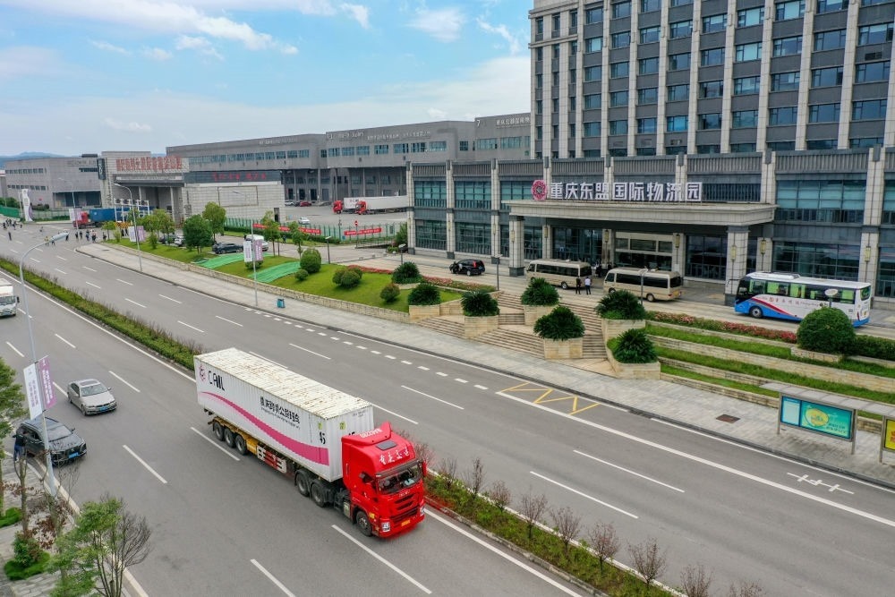 2023年10月11日，滿載筆記本電腦配件、發(fā)電機(jī)組件等產(chǎn)品的西部陸海新通道跨境公路班車從重慶南彭公路保稅物流中心駛出，將途經(jīng)廣西憑祥，直達(dá)越南（無人機(jī)照片）。新華社記者 黃偉 攝