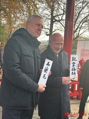 柏林市長韋格納（右）、動物園監(jiān)事會主席布魯克曼（左）手持中國文化中心工作人員現(xiàn)場手書的中文名字。人民網(wǎng)記者 徐馨攝