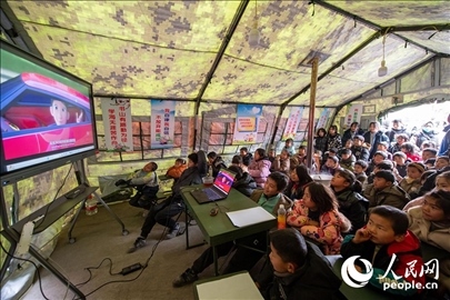 12月22日，在積石山縣大河家鎮(zhèn)大河村安置點，陸軍76集團軍某旅搭建的“臨時學?！眱?nèi)，小朋友正在看動畫片。人民網(wǎng)記者 翁奇羽攝