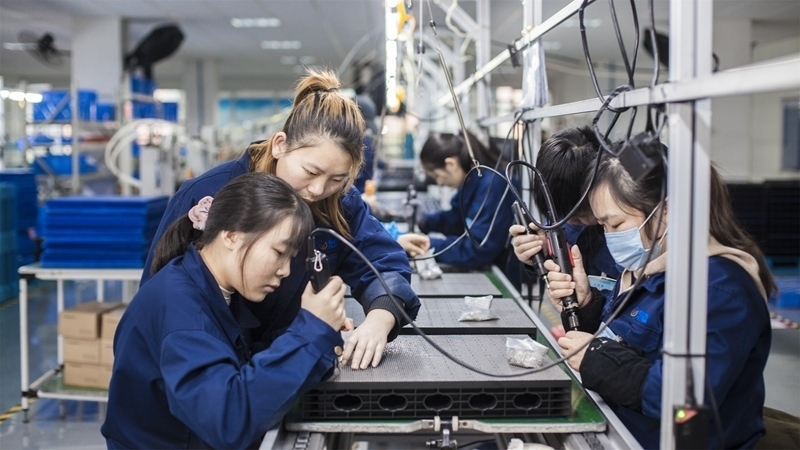 在新亞勝光電的產(chǎn)品線上，工人正進行產(chǎn)品組建和安裝布線。受訪者供圖