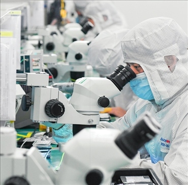 在位于武漢中國光谷的光電器件研發(fā)制造商——武漢光迅科技股份有限公司生產(chǎn)車間內(nèi)，技術人員在光模塊生產(chǎn)線作業(yè)（2023年4月11日攝）。程敏攝/本刊