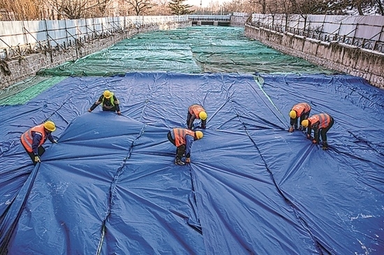 1月3日，房山區(qū)東風(fēng)街道，工人正在修復(fù)的河道內(nèi)給混凝土鋪設(shè)保溫布。