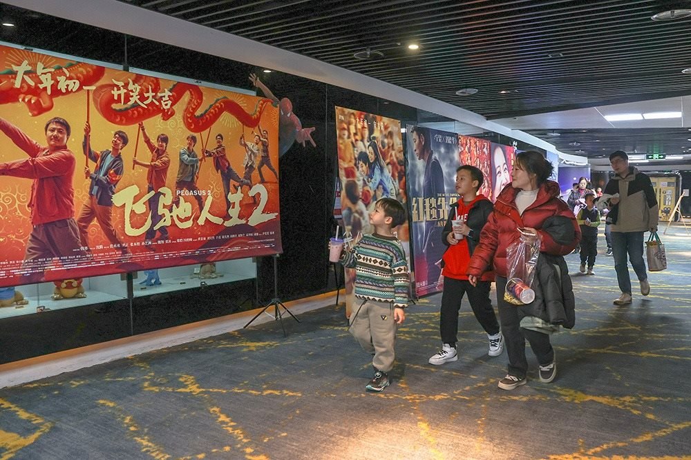 △ 2024年2月16日，在江西贛州一家電影院，觀眾從春節(jié)檔電影的宣傳展板前走過(guò)。