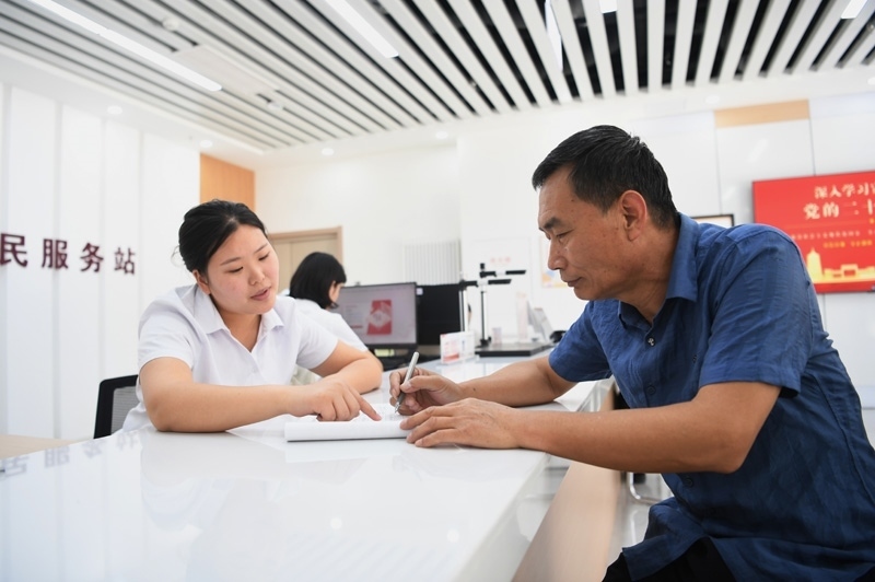 2023年5月23日，河北雄安新區(qū)容東片區(qū)南文營社區(qū)居民（右）在社區(qū)便民服務站辦理業(yè)務。