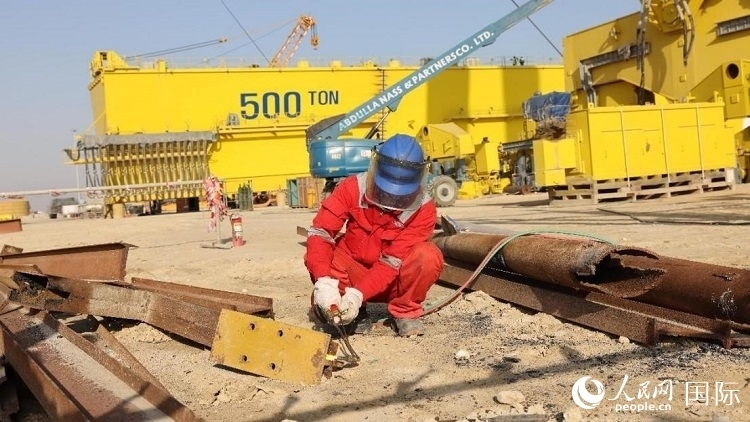 工人正在龍門吊吊裝現(xiàn)場切割金屬件。人民網(wǎng)記者管克江攝