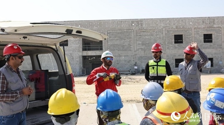 穆薩瓦爾(圖中紅衣人）現(xiàn)場演示工具操作規(guī)范。人民網(wǎng)記者 管克江攝