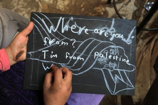 2023年12月28日，一名學(xué)生在加沙地帶南部城市拉法一所學(xué)校的臨時(shí)教室中寫下“我來自巴勒斯坦”的字樣。新華社發(fā)（里澤克·阿卜杜勒賈瓦德攝）