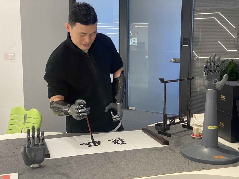 2024年3月29日，在浙江強(qiáng)腦科技有限公司展廳內(nèi)，失去雙手的產(chǎn)品體驗(yàn)官倪敏成依靠智能仿生手寫毛筆字。新華社記者 魏一駿 攝