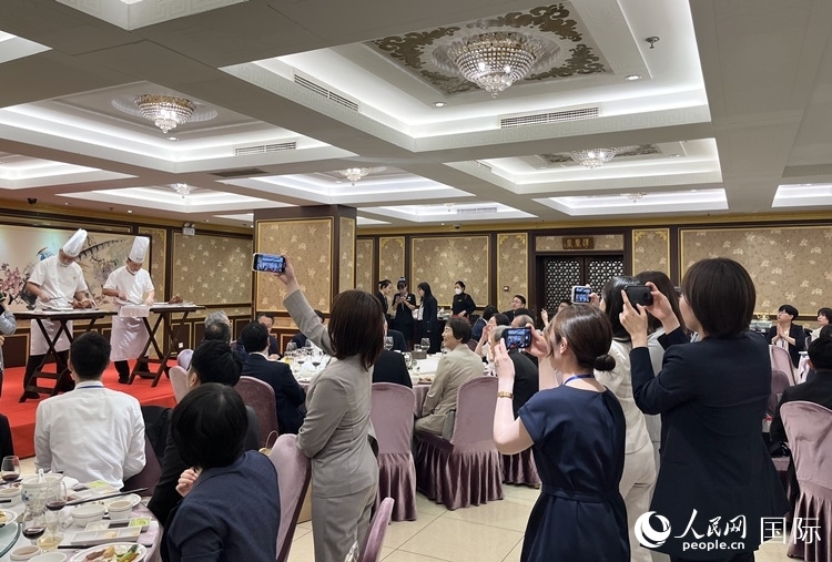 國家級(jí)非物質(zhì)文化遺產(chǎn)、全聚德片鴨工藝吸引代表團(tuán)成員拍照留念。