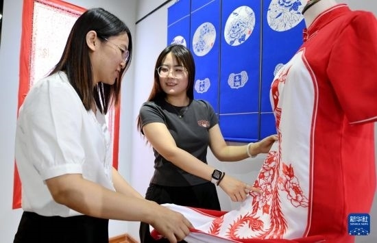 5月31日，在衡水市阜城縣一家剪紙工作室，游客在觀賞帶有剪紙?jiān)氐钠炫邸? width=