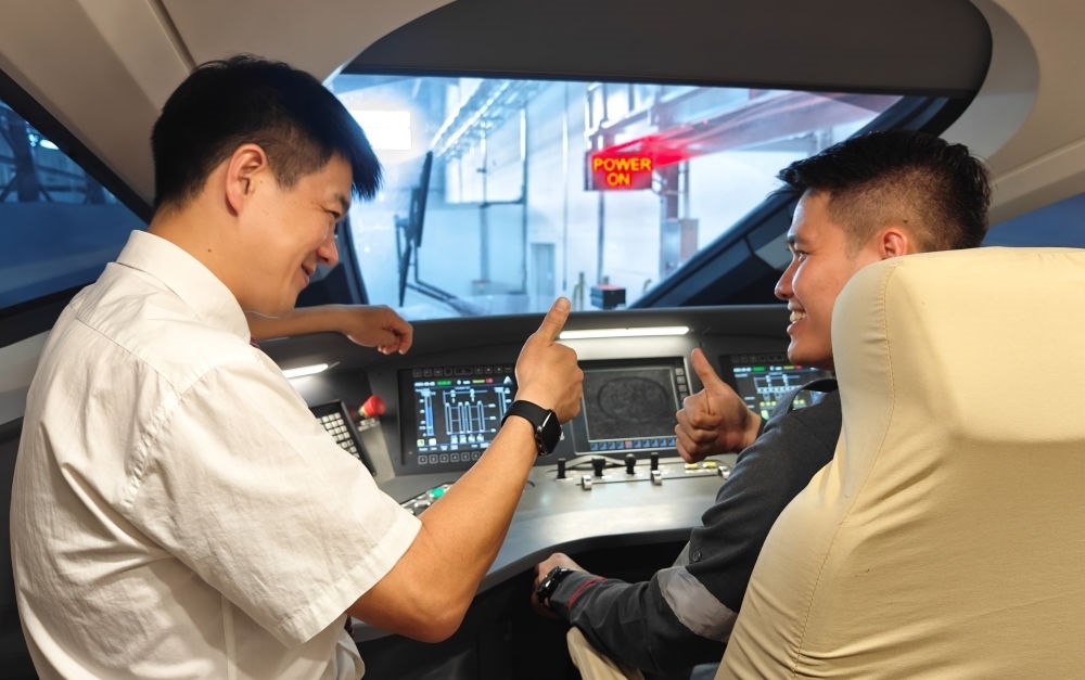 2023年8月25日，在印度尼西亞萬隆的雅萬高鐵德卡魯爾動車所內(nèi)，中國師傅穆振（左）向印尼火車司機塞蒂亞萬講解動車組出庫前的上電作業(yè)。新華社記者 徐欽 攝