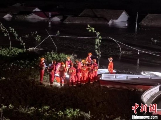  7月6日凌晨3時，在湖南岳陽華容縣團洲垸洞庭湖一線堤防，救援人員剛剛完成一次救援任務(wù)，遠(yuǎn)處是被淹的民房。中新社記者 白祖偕 攝