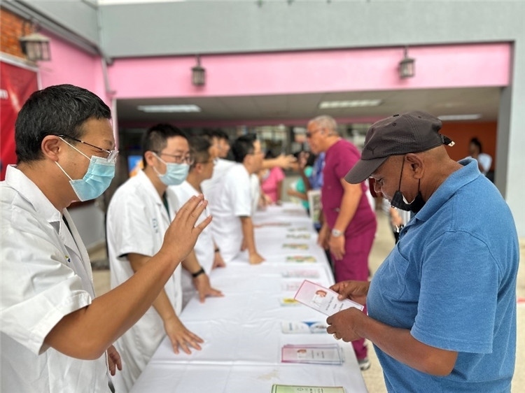 援圭醫(yī)療隊(duì)隊(duì)員們在啟動(dòng)儀式上為當(dāng)?shù)孛癖姺职l(fā)宣傳手冊。中國援助圭亞那醫(yī)療隊(duì)供圖