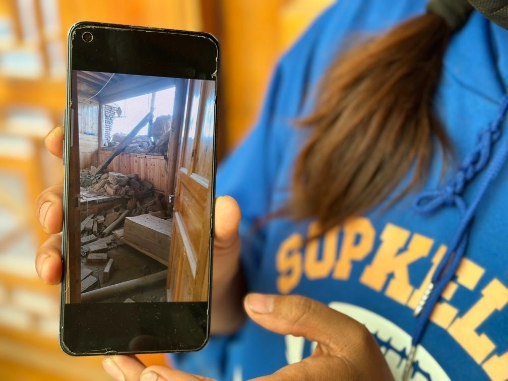 圖為7月17日拉毛東智在手機(jī)上找出地震后房屋受損的照片。新華社記者 張子琪 攝