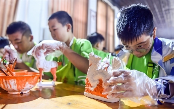 小朋友們在洛陽市孟津區(qū)朝陽鎮(zhèn)南石山村體驗唐三彩素胎施釉技藝。圖片來源：視覺中國