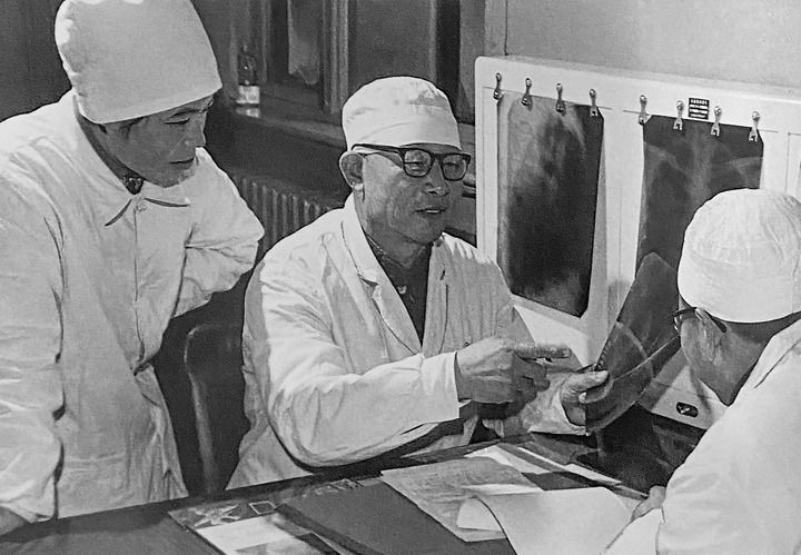 1980年1月16日，中日友好醫(yī)院首任院長(zhǎng)辛育齡（中）在內(nèi)蒙古結(jié)核病院與胸外科醫(yī)師討論病例（翻拍照片）。 新華社發(fā)