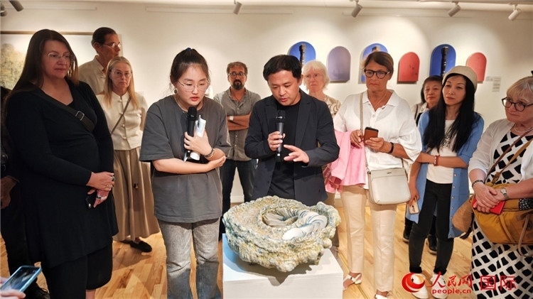 參展人、景德鎮(zhèn)陶瓷大學(xué)設(shè)計(jì)藝術(shù)學(xué)院副院長(zhǎng)余劍峰（中）向來(lái)賓介紹參展作品。人民網(wǎng)記者 殷淼攝