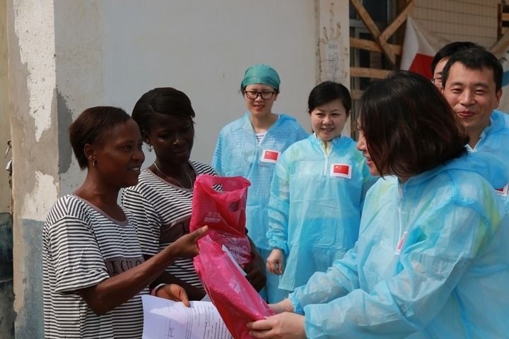 2015年4月4日，在位于塞拉利昂首都弗里敦市郊的中塞友好醫(yī)院埃博拉診療中心，中國(guó)第四批援塞醫(yī)療隊(duì)副隊(duì)長(zhǎng)邵蔚（右前）向被治愈的埃博拉出血熱患者贈(zèng)送禮物。新華社發(fā)（祖榮強(qiáng) 攝）