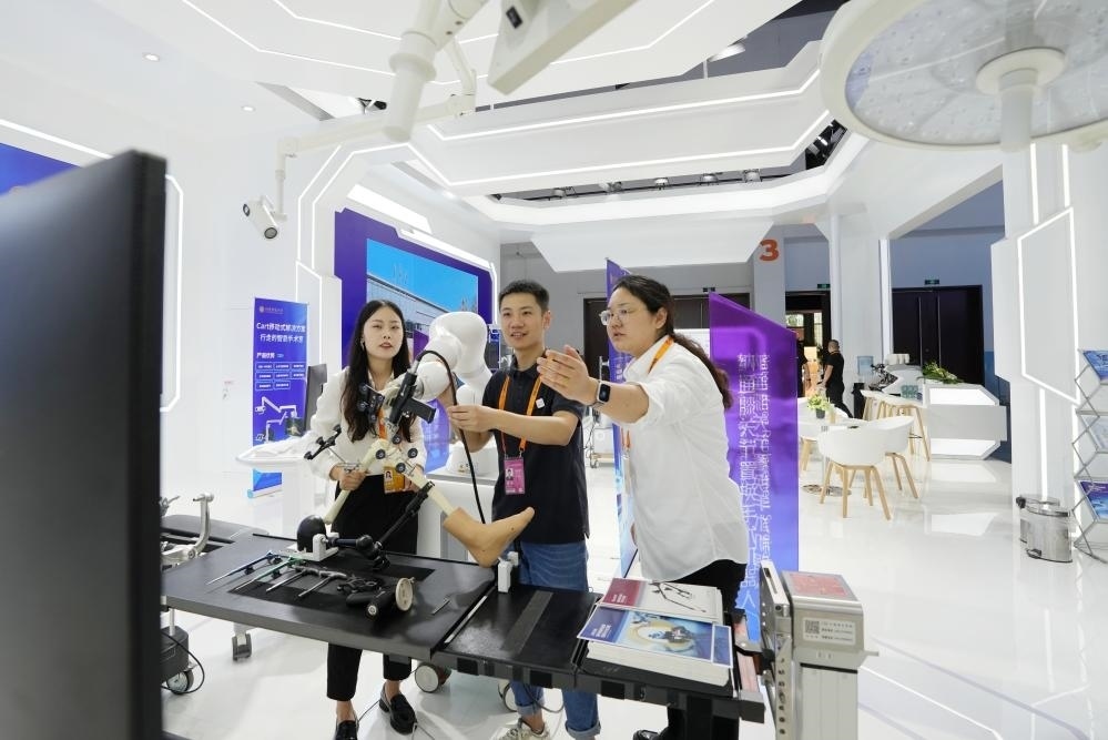 9月11日，一位媒體記者（中）在2024年服貿(mào)會國家會議中心會場體驗北京納通科技集團有限公司的膝關(guān)節(jié)置換手術(shù)機器人。新華社記者鞠煥宗 攝
