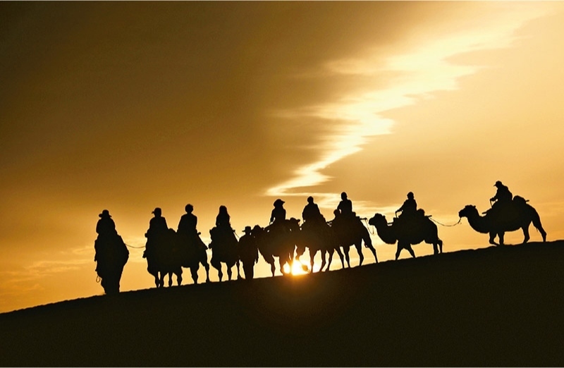 新時代以來，文化和旅游深度融合發(fā)展體制機(jī)制不斷健全，成功走出了一條獨具特色的中國旅游發(fā)展之路。圖為2024年9月1日清晨，游客在甘肅省敦煌市鳴沙山月牙泉景區(qū)乘騎駱駝，欣賞大漠風(fēng)光，體驗絲路風(fēng)情。 新華社發(fā) 張曉亮/攝