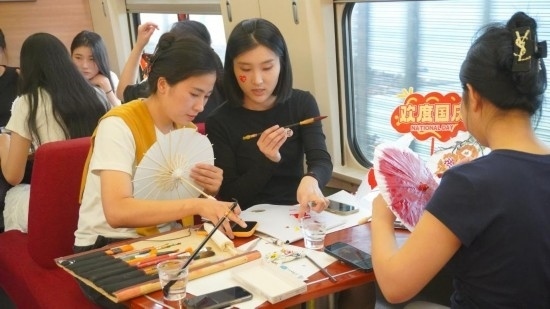 10月1日，旅客們在G1634次列車上給油紙傘作畫。新華社記者周義 攝