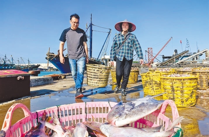 許小斌（左）和漁民一起搬運(yùn)海鮮。本報(bào)記者 付 文攝