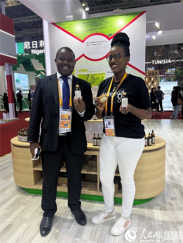 6月6日，布隆迪駐華大使館一等參贊布利馬索·阿爾弗雷德 (左，Bulimaso Alfred) 和參展商卡馬里扎·埃斯特拉 (Kamariza Estella) 在第七屆中國(guó)國(guó)際進(jìn)口博覽會(huì)布隆迪館展示當(dāng)?shù)厣a(chǎn)的辣木油。（人民網(wǎng) 艾里士 攝）