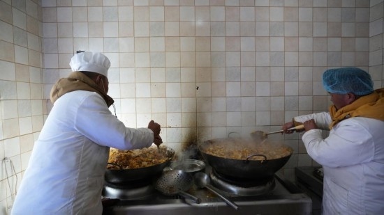 1月14日，服務(wù)隊(duì)的兩名廚師正在為村民們做午飯。新華社記者 邱星翔 攝