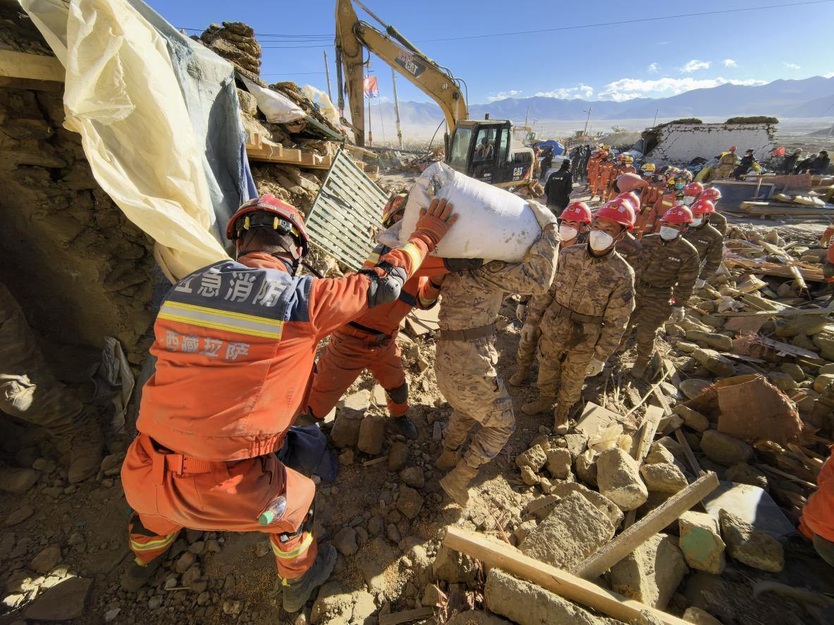 1月11日，定日縣長(zhǎng)所鄉(xiāng)古榮村，應(yīng)急消防等救援人員排隊(duì)接力搶運(yùn)掩埋在倒塌房屋下的群眾財(cái)物。人民日?qǐng)?bào)記者楊翹楚攝