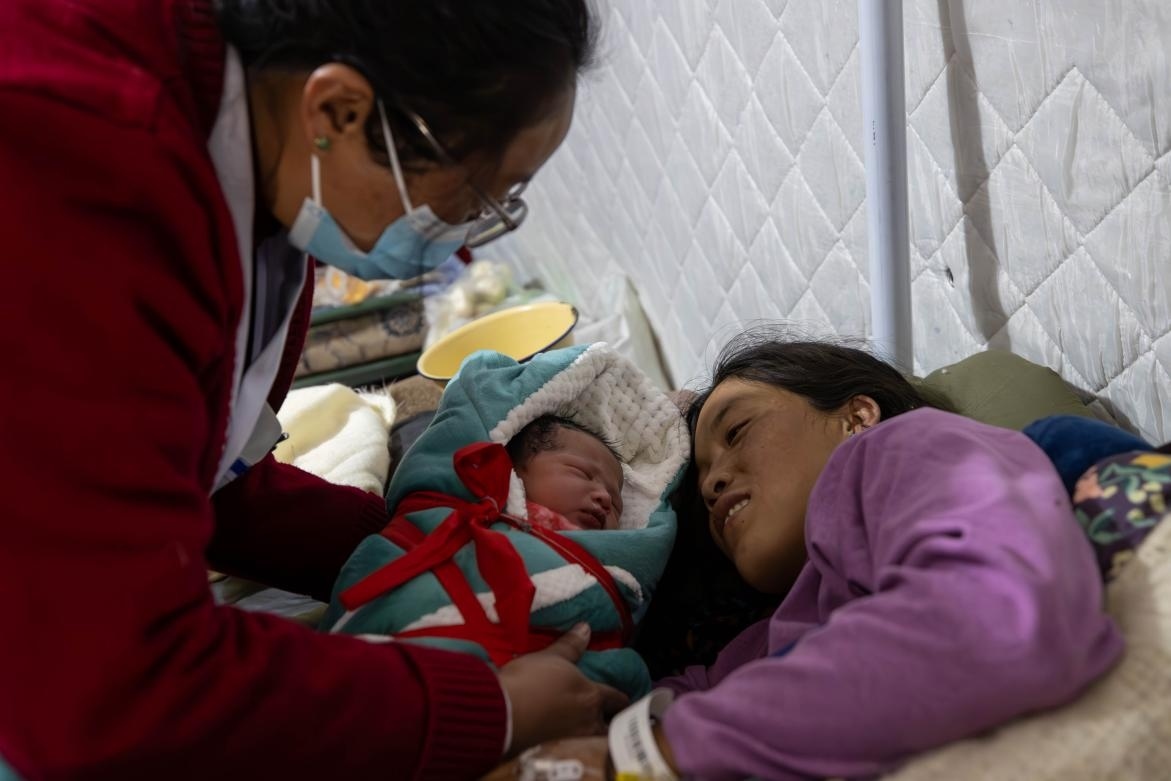 1月10日，定日縣中心醫(yī)院的婦產(chǎn)科醫(yī)生悉心照看一位母親和她懷里的新生兒。人民日?qǐng)?bào)記者張武軍攝