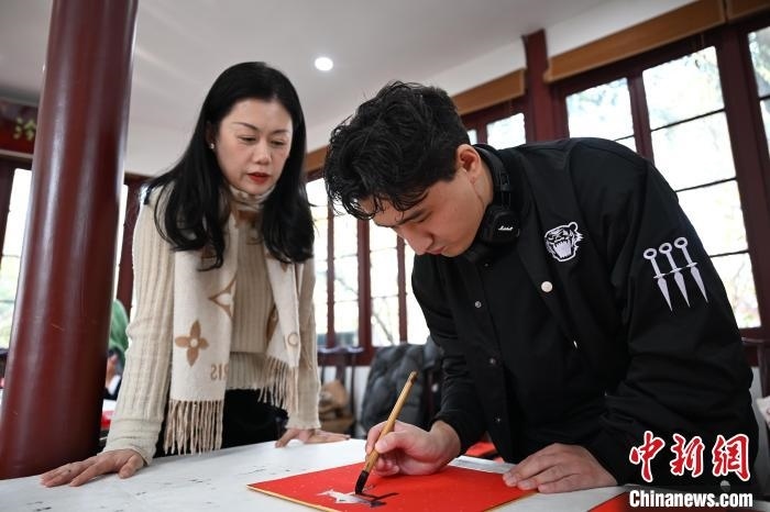 1月20日，外籍留學(xué)生在西泠印社社員李硯指導(dǎo)下寫福。當(dāng)日，來自巴西、馬來西亞、加納、哈薩克斯坦的外籍留學(xué)生在浙江杭州西泠印社體驗(yàn)福貼、春聯(lián)和篆刻，感受古老的中國傳統(tǒng)文化。中新社記者 王剛 攝